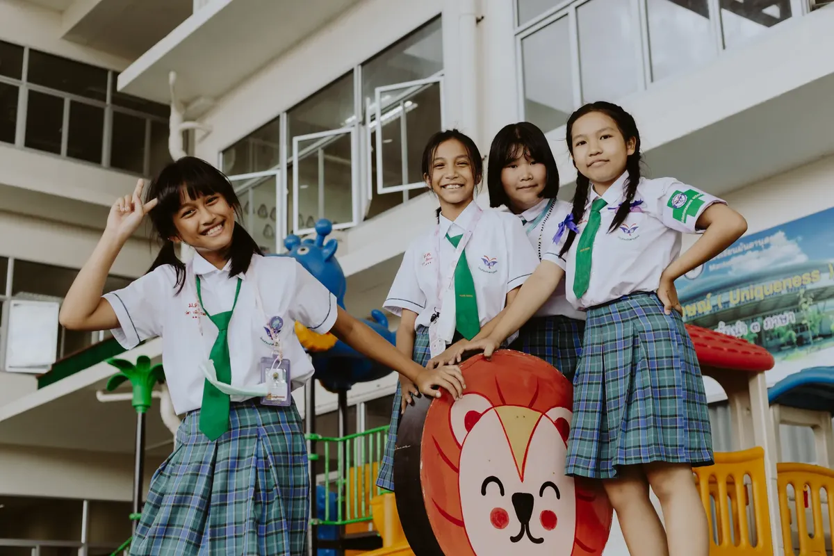Smiling children in school uniforms pose together in a school playground, exuding happiness and friendship.