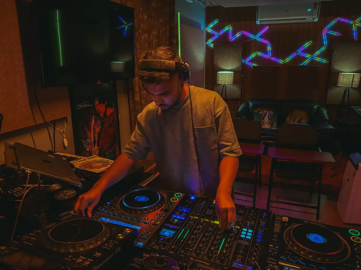 DJ performing live music set in a vibrant studio with neon lights and professional equipment.